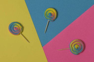 Renkli Kağıt arka plan üzerinde renkli, el yapımı girdap lolipop yaz renkleri yaratıcı görünümü. Kavramsal görüntü yazın. Minimalizm. Soyutlama. Yaratıcılık. Üstten görünüm.