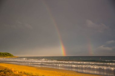 Günbatımı ve gökkuşağı Platja Llarga plajı, Tarragona, İspanya