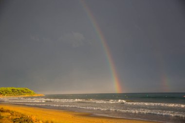 Günbatımı ve gökkuşağı Platja Llarga plajı, Tarragona, İspanya