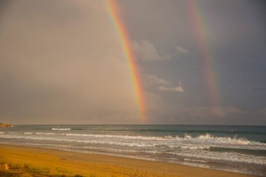 Günbatımı ve gökkuşağı Platja Llarga plajı, Tarragona, İspanya