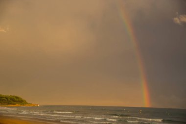 Günbatımı ve gökkuşağı Platja Llarga plajı, Tarragona, İspanya