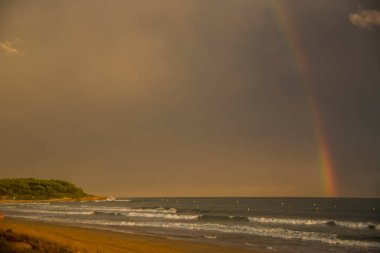 Günbatımı ve gökkuşağı Platja Llarga plajı, Tarragona, İspanya