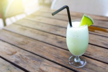 Eski ahşap masada kavun dilimleri ile bardakta kavun püresi. # Tatlı, serin, taze bir his veriyor #.