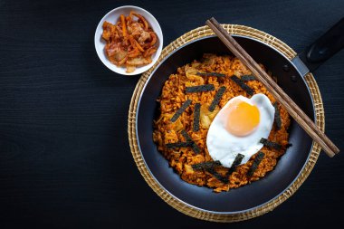 Ev yapımı Kimchi Kızarmış pilav tavada yumurta, tepede siyah ahşap masa..