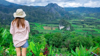 Dağın tepesinde duran kadın dağın panoramik manzarasına bakıyor..