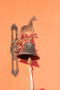 Kapıda at heykeli olan metal tabela hoş geldiniz. -Kırmızı duvar arka planı.