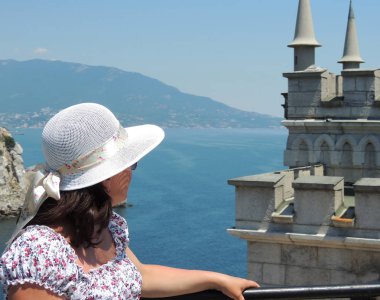 Woman in a hat looking at castle swallow's nest and the sea in the Crimea       