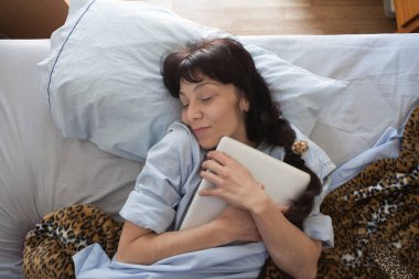 Yatakta yatan genç bir kadın, uykusundan yeni kalkmış ve dizüstü bilgisayarı yataktaydı. Kendine dikkat et..