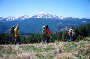 Dağ yolunda yürüyen tecrübeli yürüyüşçüler. Dağlara tırmanma teçhizatı ile donatılmış bir grup arkadaş. Karlı dağların manzarası.