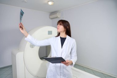 Genç bayan radyologlar tomografi odasında kalıyorlar. Klinikte çalışıyorum. Güzel doktor MRI taramasına bakıyor. Beyaz takım elbiseli bir doktor. Üniformalı Radyolog.