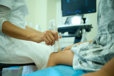 Pediatrik ultrason taraması. Çocuk ultrasonu. Çocuk doktoru bacağını tarıyor. Doktorun çocuk için bacak sonogramı yapmasına yakın çekim. İskelet sisteminin ultrason incelemesi. Eklem hastalıkları konsepti