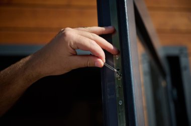 Yeni bir inşaat sahasına kapı ve pencere döşeyen işçilerin yakın görüntüsü. Büyülü anahtarı olan üniformalı bir adam yeni güzel evin ön cam kapısını ve pencerelerini ayarlıyor. Ekin görünümü.