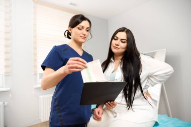 Tıbbi muayeneden geçen hamile bir kadın. Kadın doktor hamile kadına danışıyor. Fetüs bakımı.