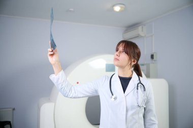 Genç bayan radyologlar tomografi odasında kalıyorlar. Klinikte çalışıyorum. Güzel doktor röntgen, röntgen, tomografi ve MRI 'ya bakıyor. Üniformalı doktor.