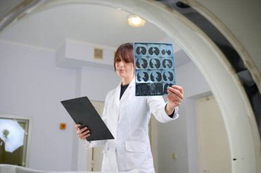 Genç bayan radyologlar tomografi odasında kalıyorlar. Klinikte çalışıyorum. Güzel doktor röntgen, röntgen, tomografi ve MRI 'ya bakıyor. Üniformalı doktor.