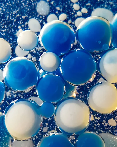 Yağ içinde su kabarcıkları. Mavi ve beyaz su damlaları şeffaf mavi arkaplan üzerinde