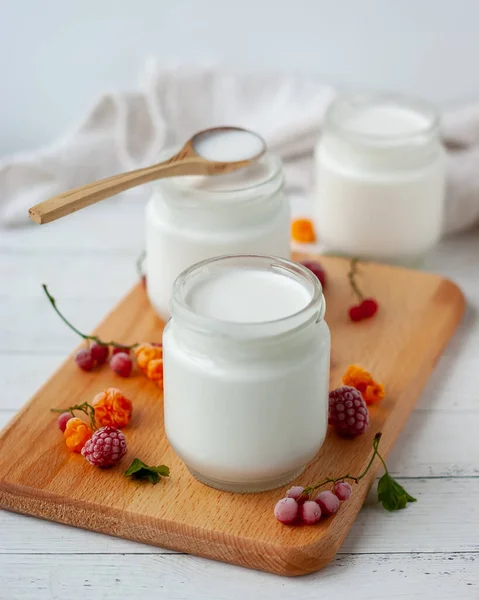 Doğal ev yapımı hindistan cevizli yoğurt ve ahşap bir arka planda cam kavanozda taze böğürtlen.
