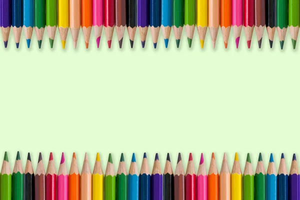 Color pencils on a green background. With free space for text. To visual design for education, learning, public relations about art activities in schools.