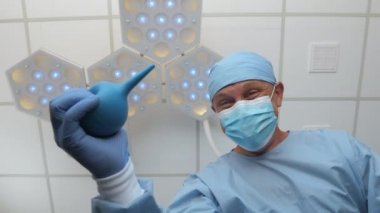 Elinde lavman olan bir doktor hastanın üstünde durur..