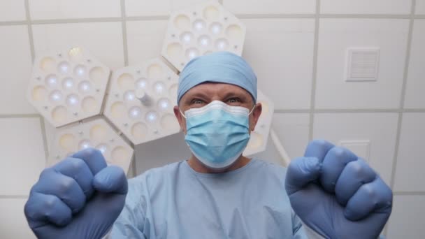 Médico irritado em luva de borracha fica sobre paciente na sala de cirurgia — Vídeo de Stock