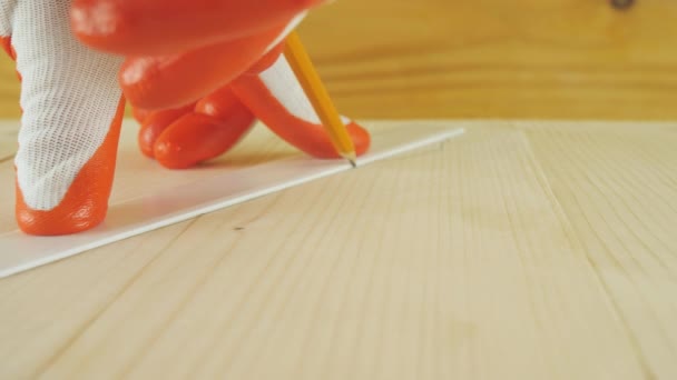 Een man tekent een lijn met een potlood op een houten oppervlak. — Stockvideo