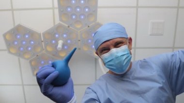 Elinde lavman olan bir doktor hastanın üstünde durur..