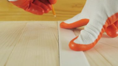 Bir adam tahta bir yüzeye kalemle bir çizgi çizer..