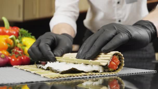Cocinar las manos haciendo rollo de sushi japonés con estera de bambú. — Vídeos de Stock