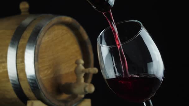 Rött vin rinner från flaskhalsen ner i glaset — Stockvideo