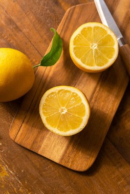 Bıçak ve kesme tahtasıyla ahşap bir masada limonlar