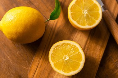 Bıçak ve kesme tahtasıyla ahşap bir masada limonlar
