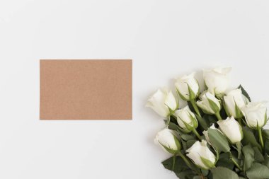 Beyaz bir masanın üzerinde bir buket gül olan bir el işi kartının üst görüntüsü..