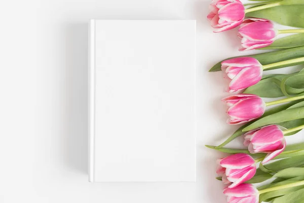 Beyaz Masa Üzerinde Pembe Laleler Olan Beyaz Kitap Modelinin Üst — Stok fotoğraf
