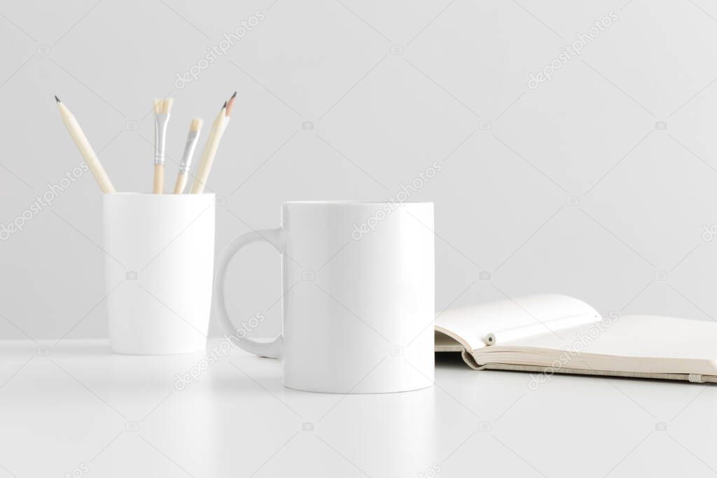 Mug mockup with workspace accessories on a white table.