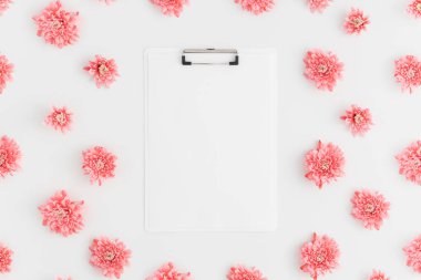 Beyaz arka planda pembe kasımpatı süslemesi olan beyaz bir panonun üst görünümü.