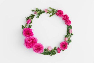 Beyaz arka planda pembe güllerden ve yeşil dallardan yapılmış çiçek çelengi..