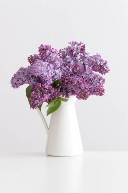 Beyaz bir masadaki vazoda bir demet leylak çiçeği.