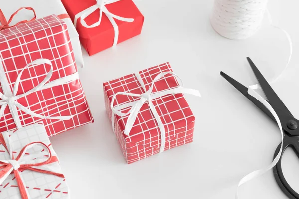 Rot Weiße Weihnachtsgeschenke Mit Schere Und Bindfaden Auf Weißem Tisch — Stockfoto