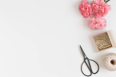 Çalışma alanı aksesuarları ve bir buket pembe karanfil beyaz bir masada. Boş kopya alanı ile düz yatıyordu.