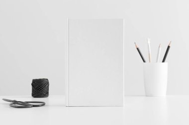 Beyaz masa üzerinde çalışma alanı aksesuarları olan beyaz kitap modeli.