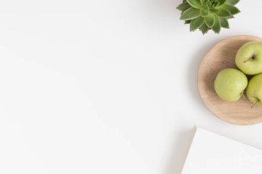 Lezzetli bir bitki, elmalar ve beyaz bir masada bir kitap. Boş kopya alanı ile düz yatıyordu.