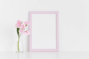 Pembe çerçeve modeli, pembe zakkum beyaz bir masa üzerinde cam bir vazoda. Portre oryantasyonu..