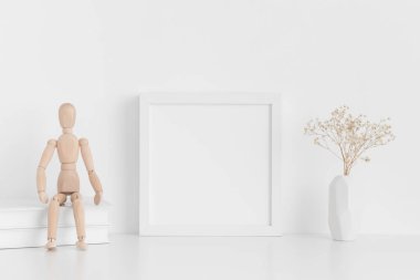 Beyaz kare çerçeve, kitaplar, manikinler ve beyaz masadaki vazoda bir çingene resmi..