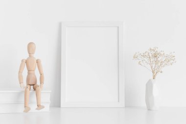 Beyaz çerçeveli, içinde kitaplar, manikin ve vazoda bir çingene resmi olan beyaz bir çerçeve..