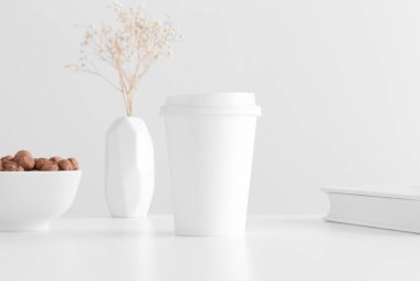 Kahve fincanı, vazoda bir çingene fındık ve beyaz bir masada bir kitap..