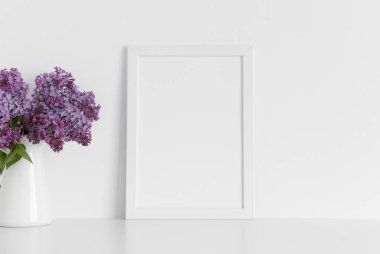 Beyaz çerçeveli bir vazoda bir demet leylak ve beyaz bir masa. Portre oryantasyonu..