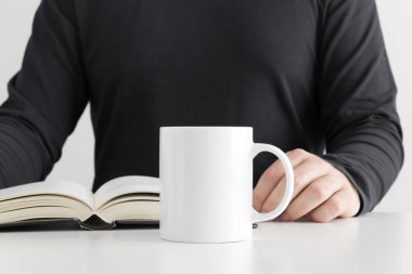 Beyaz kupa, kitap okuyan bir adamla..