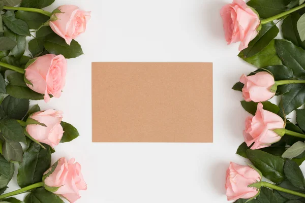 Top Kilátás Egy Kraft Kártya Mockup Rózsaszín Rózsákkal Egy Fehér — Stock Fotó