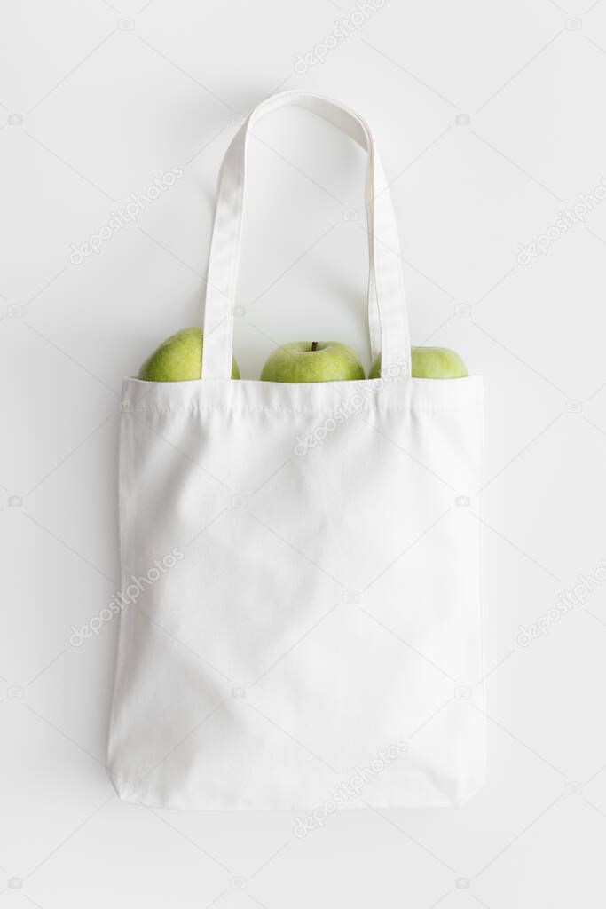 White tote bag mockup with apples on a white table.