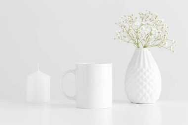 Beyaz bir masa üzerinde bir mum ve bir çigila ile kupa modeli.